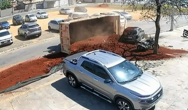 Terra de caminhão tomba em curva e soterra carro estacionado em Aparecida de Goiânia