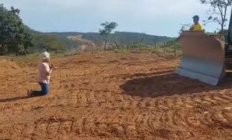 Idosa se ajoelha diante de máquina em protesto contra desapropriação para obra da Go-330